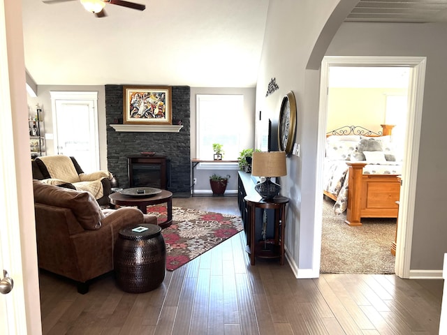 living room featuring ceiling fan, dark hardwood / wood-style flooring, and a fireplace