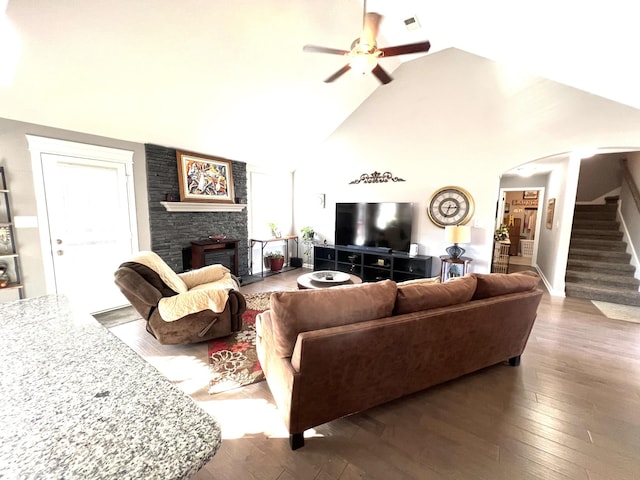 living room with a wood stove, ceiling fan, high vaulted ceiling, and wood-type flooring