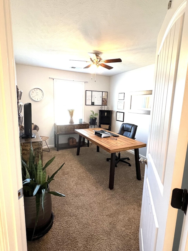 carpeted home office with a textured ceiling and ceiling fan