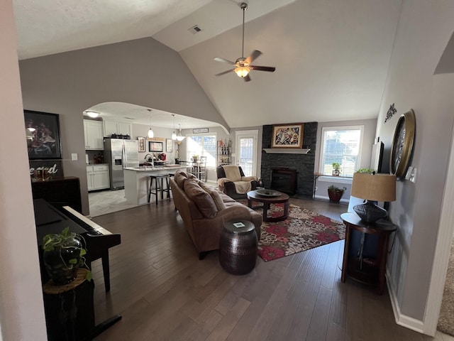 living room featuring ceiling fan, a fireplace, high vaulted ceiling, and dark hardwood / wood-style floors