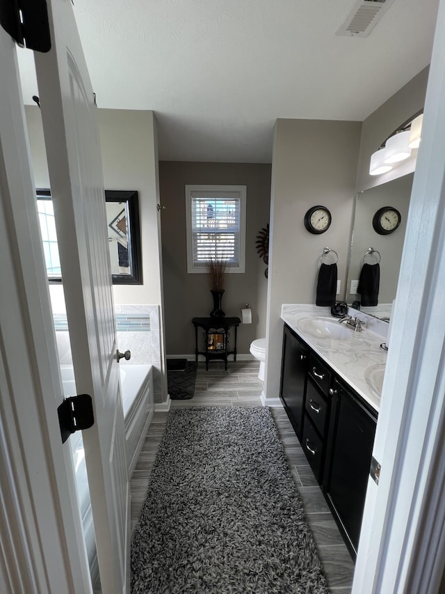 bathroom featuring a bathtub, hardwood / wood-style floors, vanity, and toilet