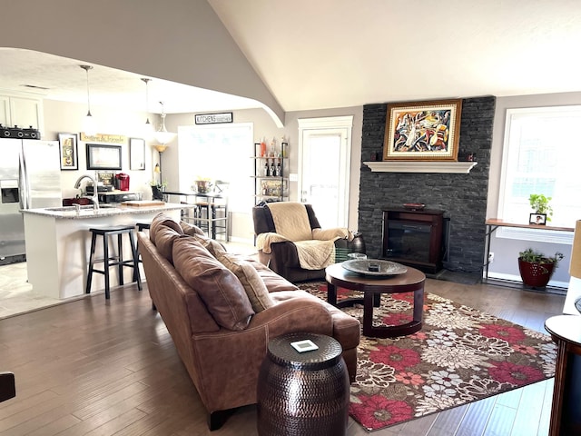 living room with a fireplace, dark hardwood / wood-style flooring, lofted ceiling, and sink