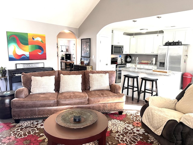 living room with hardwood / wood-style floors, vaulted ceiling, and sink