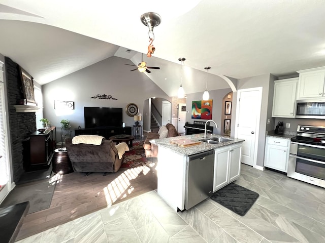 kitchen featuring white cabinetry, sink, stainless steel appliances, light stone counters, and lofted ceiling