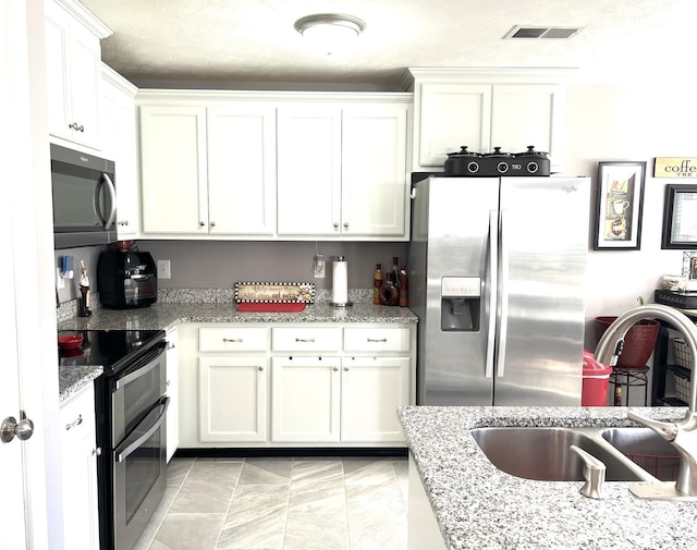 kitchen with white cabinetry, sink, light stone countertops, and appliances with stainless steel finishes