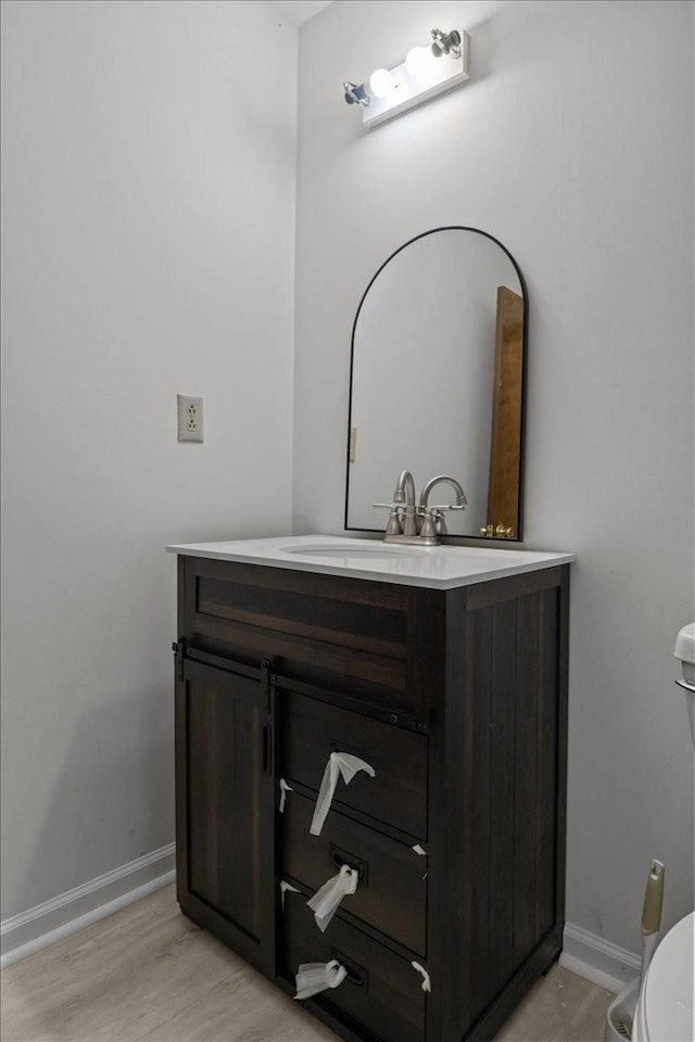 bathroom with hardwood / wood-style floors, vanity, and toilet