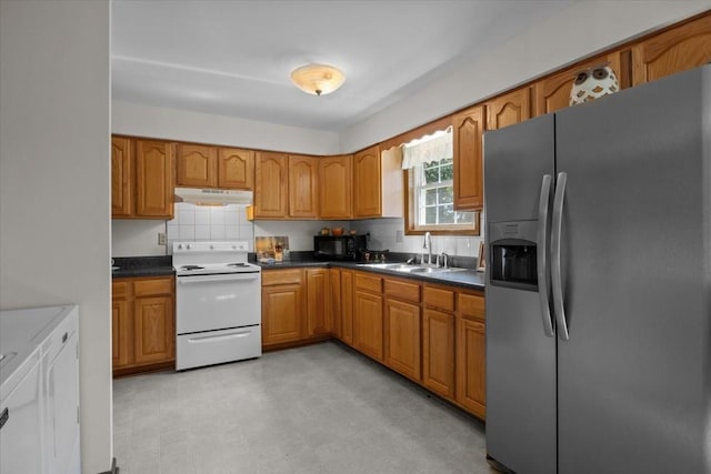 kitchen with stainless steel fridge, backsplash, sink, white electric stove, and washing machine and clothes dryer