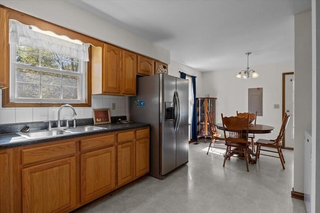 kitchen with sink, hanging light fixtures, tasteful backsplash, a notable chandelier, and stainless steel fridge