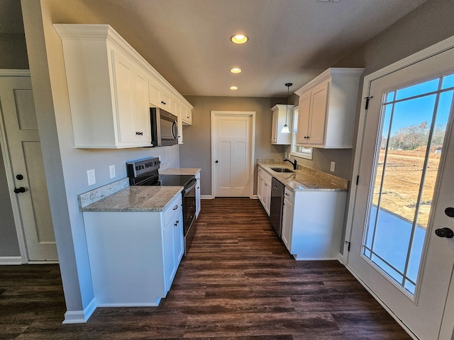 kitchen featuring dark wood-type flooring, sink, hanging light fixtures, white cabinetry, and stainless steel appliances