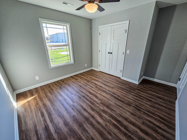 unfurnished bedroom featuring a closet, dark hardwood / wood-style floors, and ceiling fan