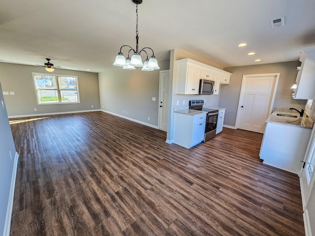 kitchen featuring dark hardwood / wood-style flooring, ceiling fan with notable chandelier, stainless steel appliances, white cabinets, and hanging light fixtures