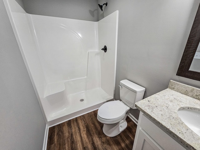 bathroom featuring walk in shower, toilet, vanity, and hardwood / wood-style flooring