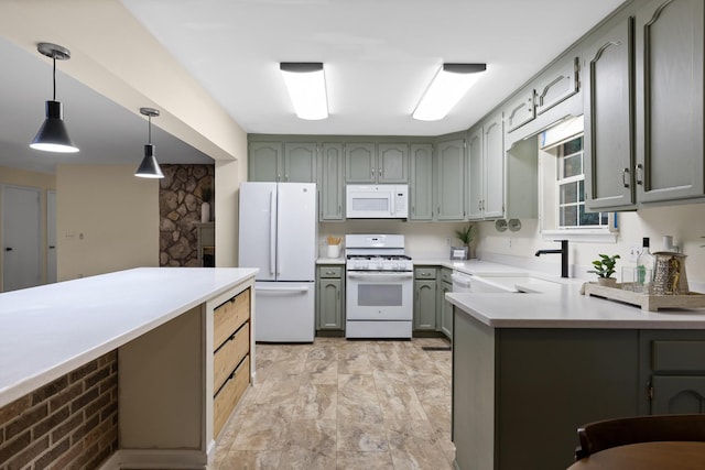 kitchen with decorative light fixtures, white appliances, sink, and kitchen peninsula