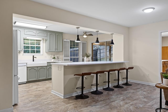 kitchen with dishwasher, sink, kitchen peninsula, pendant lighting, and a breakfast bar