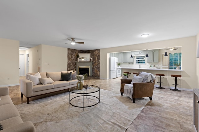 living room with ceiling fan and a stone fireplace