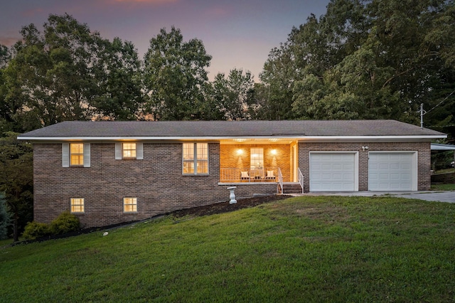 view of front of house with a yard, covered porch, and a garage