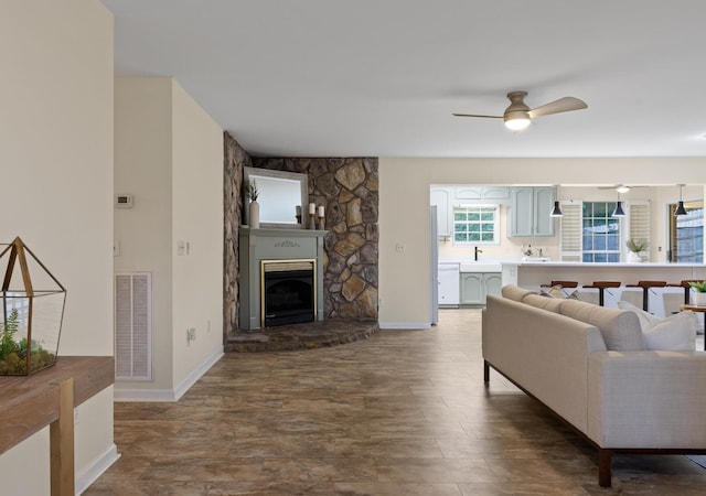 living room featuring a fireplace, ceiling fan, and sink