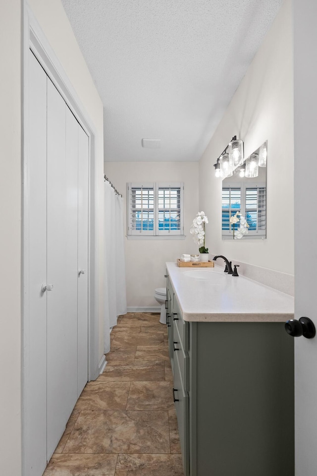 bathroom with vanity, toilet, and a textured ceiling