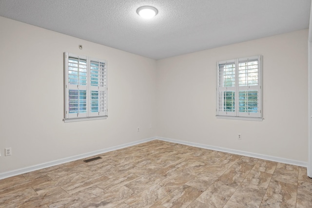 empty room featuring a textured ceiling and a wealth of natural light