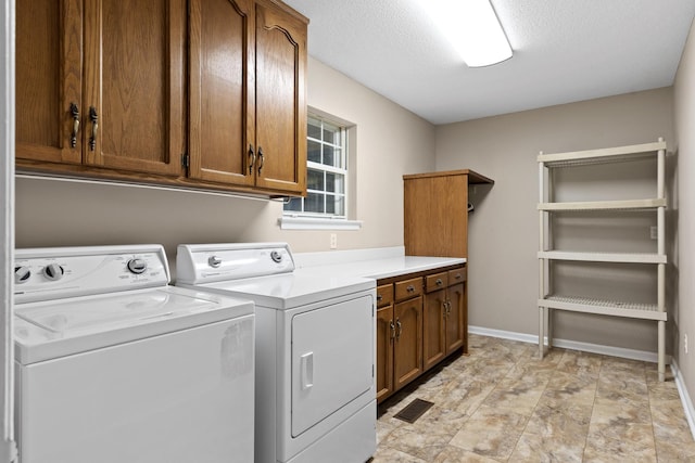 laundry room with cabinets, a textured ceiling, and washing machine and dryer