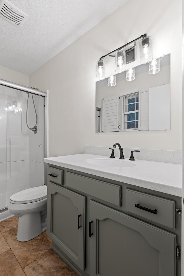 bathroom with tile patterned floors, a textured ceiling, toilet, a shower with door, and vanity