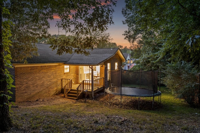 back house at dusk with a trampoline and a wooden deck