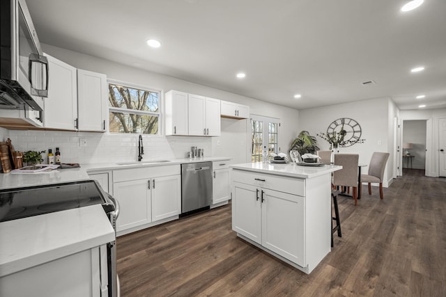 kitchen with appliances with stainless steel finishes, white cabinetry, a kitchen island, and sink