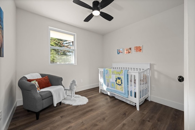 bedroom featuring dark hardwood / wood-style floors, a nursery area, and ceiling fan