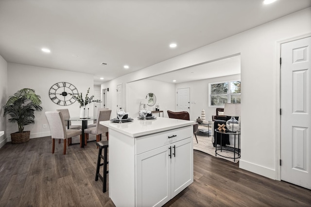 kitchen featuring dark hardwood / wood-style floors, a kitchen island, a kitchen bar, and white cabinetry