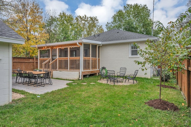 rear view of house with a sunroom, a patio area, and a lawn