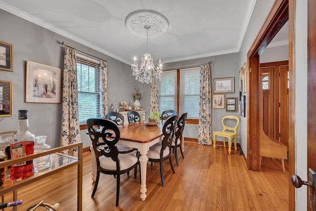 dining space with light wood-type flooring, an inviting chandelier, and ornamental molding