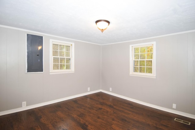 empty room featuring electric panel, hardwood / wood-style floors, and ornamental molding