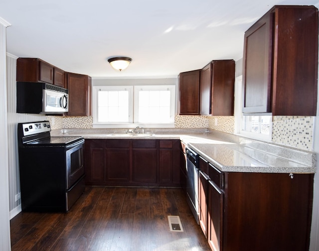 kitchen featuring dark wood-type flooring, sink, appliances with stainless steel finishes, tasteful backsplash, and dark brown cabinetry