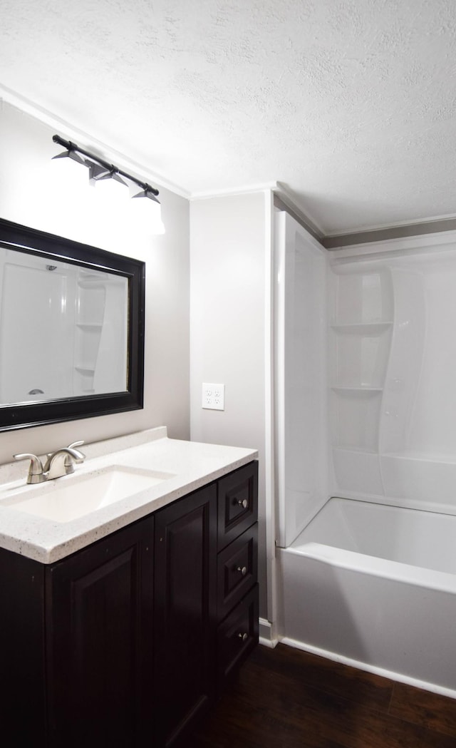 bathroom featuring hardwood / wood-style floors, vanity, washtub / shower combination, and a textured ceiling