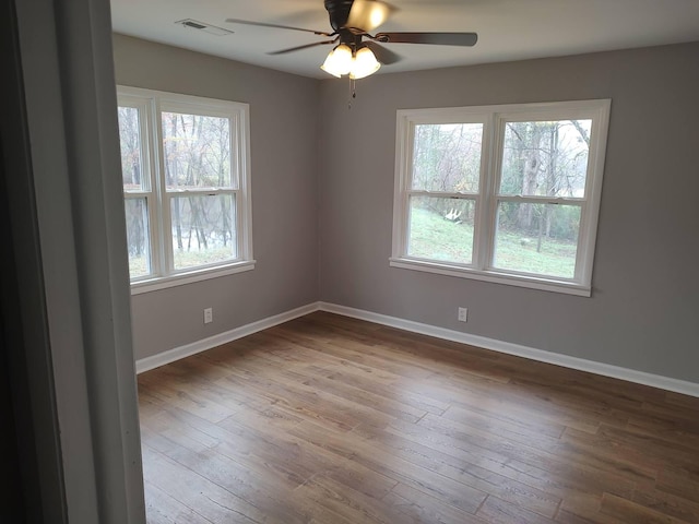 unfurnished room featuring a healthy amount of sunlight, hardwood / wood-style floors, and ceiling fan