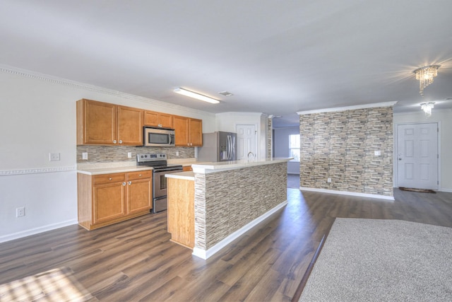 kitchen featuring dark hardwood / wood-style floors, ornamental molding, an island with sink, and appliances with stainless steel finishes