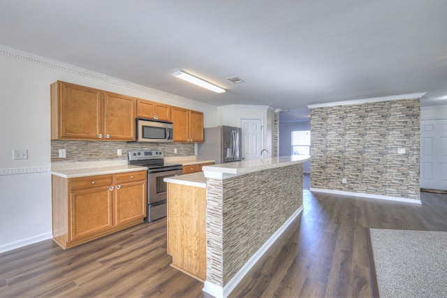 kitchen with dark wood-type flooring, sink, crown molding, appliances with stainless steel finishes, and a kitchen island