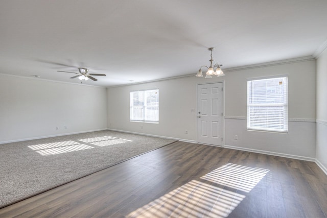 spare room with ceiling fan with notable chandelier, dark hardwood / wood-style floors, crown molding, and a healthy amount of sunlight