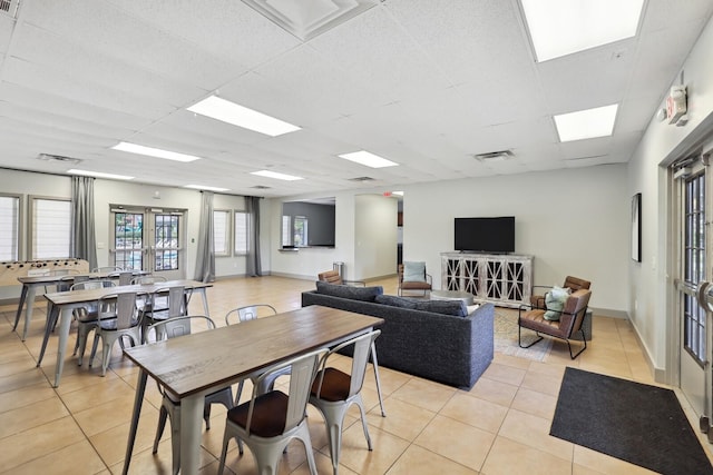 tiled living room with a drop ceiling and french doors