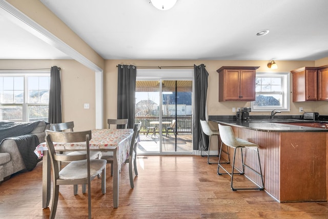 kitchen featuring dark stone countertops, hardwood / wood-style floors, a breakfast bar, and sink