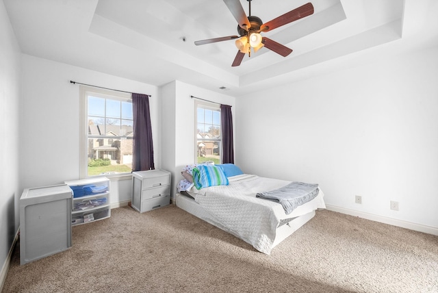 bedroom with carpet flooring, a tray ceiling, and ceiling fan