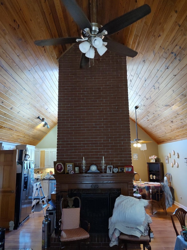 living room featuring wood ceiling, light hardwood / wood-style flooring, high vaulted ceiling, and a brick fireplace