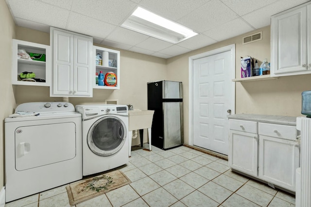 washroom with separate washer and dryer, light tile patterned flooring, and cabinets