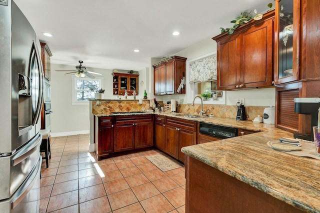 kitchen with light stone countertops, appliances with stainless steel finishes, kitchen peninsula, ceiling fan, and sink