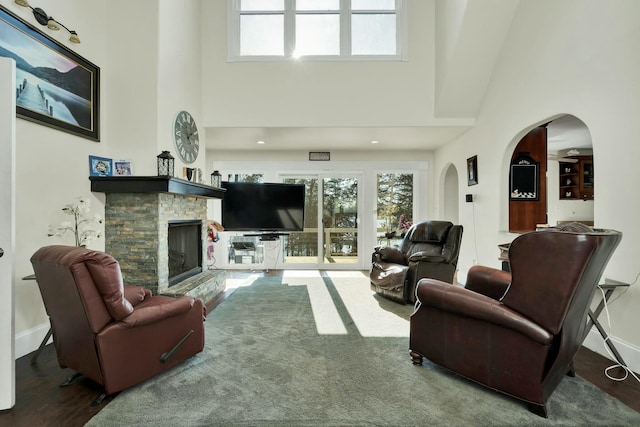 living room featuring wood-type flooring, a fireplace, and a high ceiling