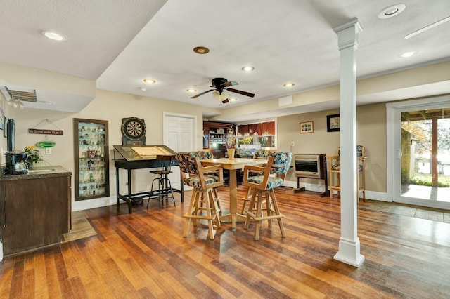 dining room with hardwood / wood-style flooring, ceiling fan, ornate columns, and heating unit