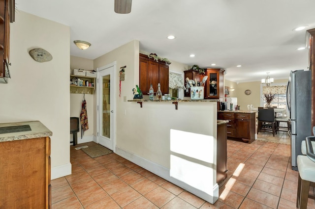 kitchen with kitchen peninsula, light tile patterned floors, stainless steel refrigerator, and hanging light fixtures