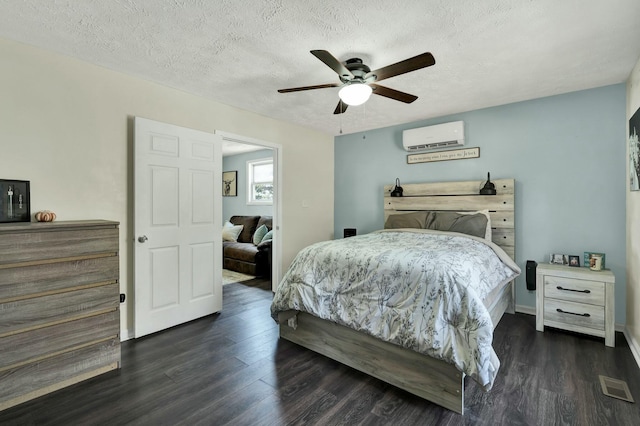 bedroom featuring a textured ceiling, an AC wall unit, ceiling fan, and dark wood-type flooring