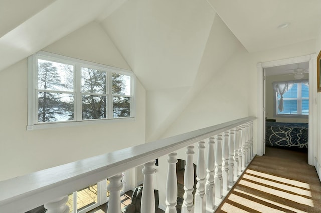 hallway with vaulted ceiling and dark colored carpet