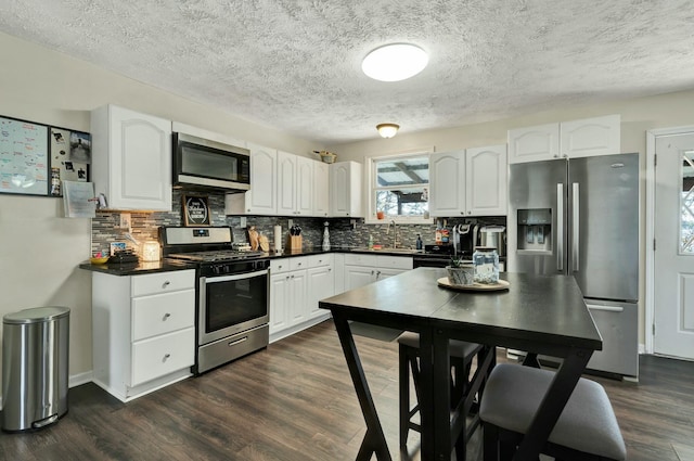 kitchen featuring decorative backsplash, white cabinetry, stainless steel appliances, and dark hardwood / wood-style floors